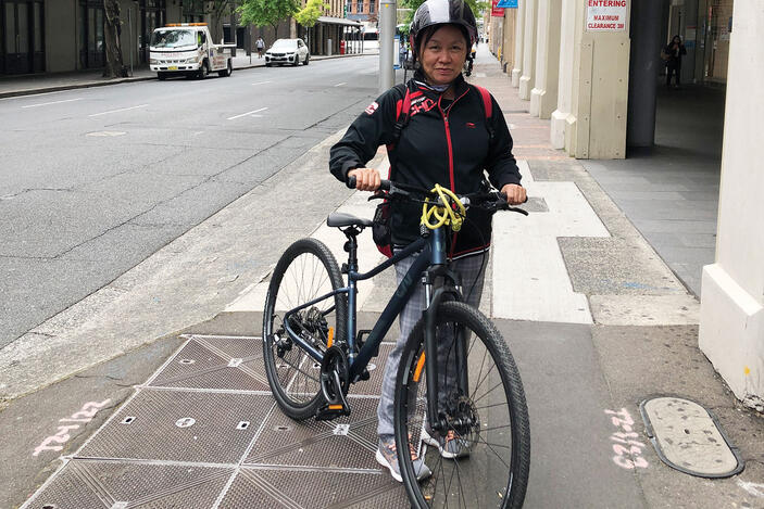 Woman wearing a bike helmet and standing next to her bike. 