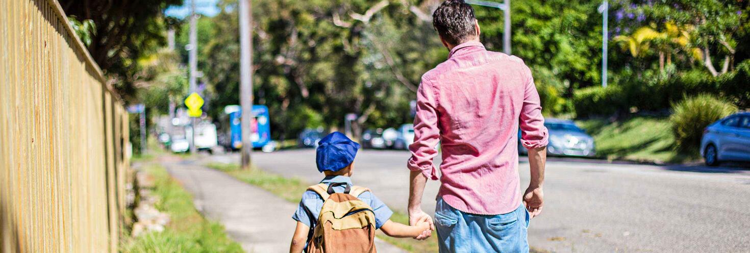 School child and father walking on a path